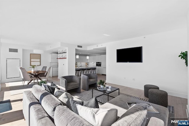 living area with visible vents, baseboards, and light wood finished floors