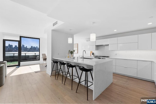 kitchen with light wood-type flooring, visible vents, a kitchen bar, and modern cabinets