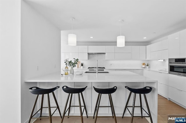 kitchen with backsplash, white cabinetry, oven, a kitchen breakfast bar, and modern cabinets