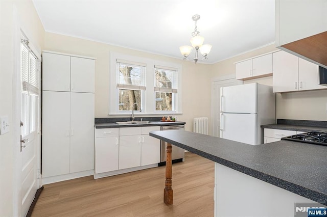 kitchen featuring a sink, dark countertops, radiator heating unit, freestanding refrigerator, and dishwasher