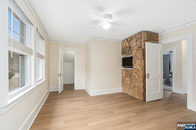 unfurnished living room with baseboards, ceiling fan, crown molding, and light wood finished floors