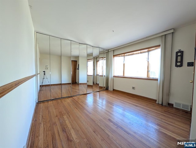 unfurnished bedroom with wood finished floors, visible vents, and baseboards