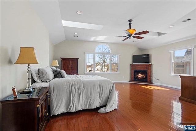 bedroom featuring visible vents, multiple windows, dark wood finished floors, and vaulted ceiling with skylight