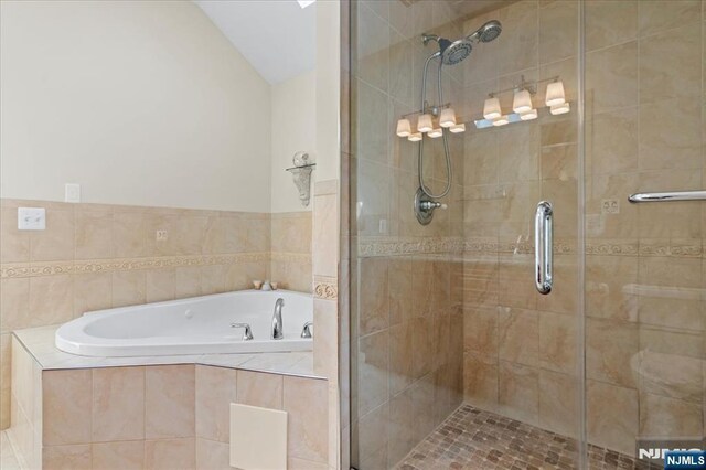 bathroom featuring a stall shower, a garden tub, and vaulted ceiling