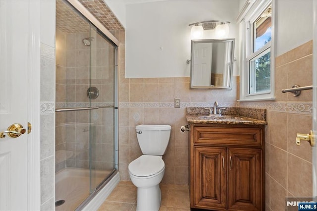 full bathroom featuring tile patterned flooring, tile walls, toilet, and a stall shower