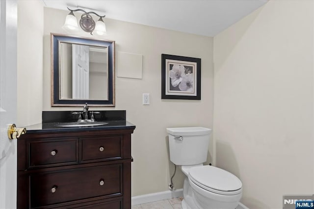 bathroom featuring toilet, vanity, and baseboards