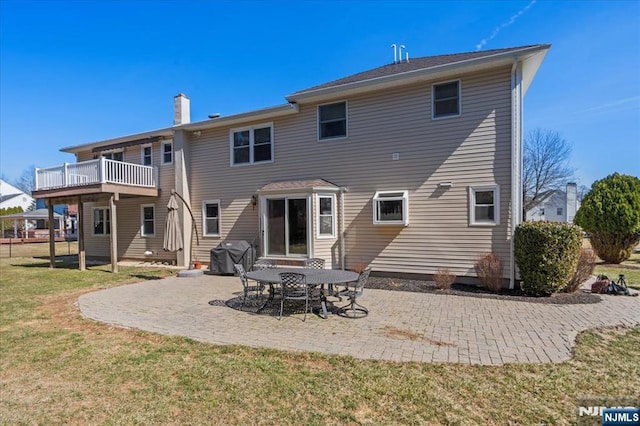 rear view of property featuring a lawn, a chimney, and a patio area