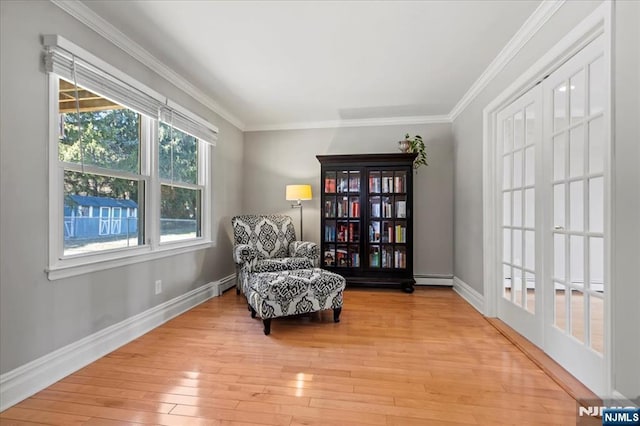 living area featuring ornamental molding, baseboards, and hardwood / wood-style flooring