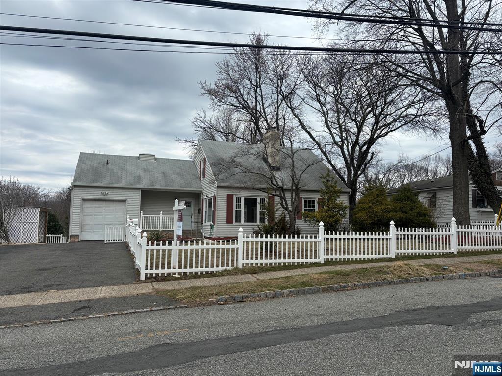 view of front facade with a fenced front yard, an attached garage, and aphalt driveway