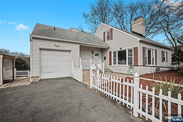 view of front of home with driveway, a chimney, a garage, and fence