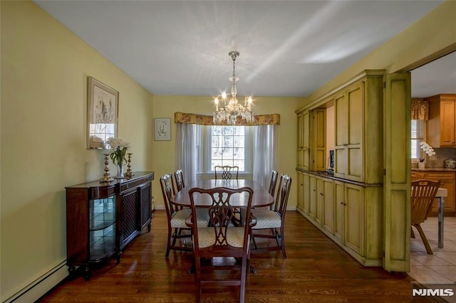 dining area featuring a baseboard heating unit, a notable chandelier, dark wood-style floors, and baseboards