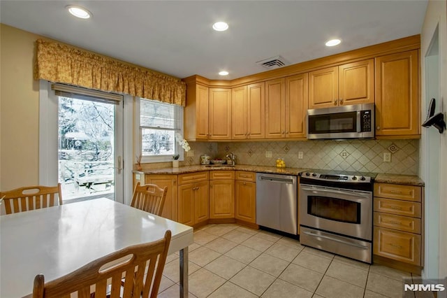 kitchen featuring backsplash, light stone countertops, light tile patterned floors, recessed lighting, and appliances with stainless steel finishes