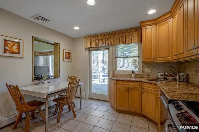 kitchen featuring tasteful backsplash, visible vents, a wealth of natural light, stainless steel stove, and a sink