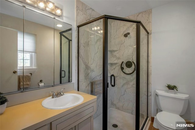 bathroom with a marble finish shower, toilet, and vanity