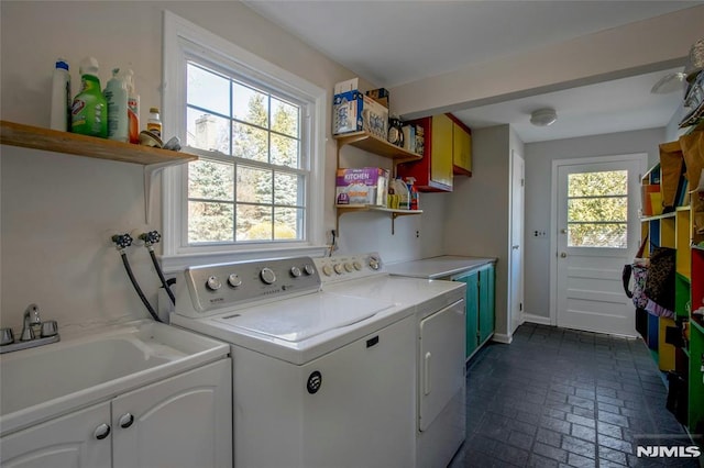 laundry area with brick floor, cabinet space, separate washer and dryer, and a sink