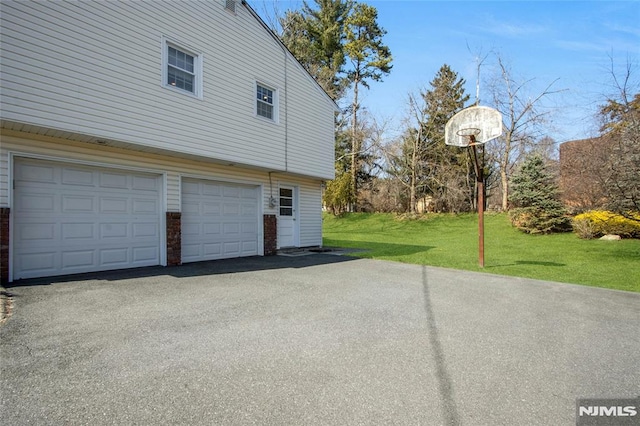 view of home's exterior with aphalt driveway, a garage, a lawn, and brick siding