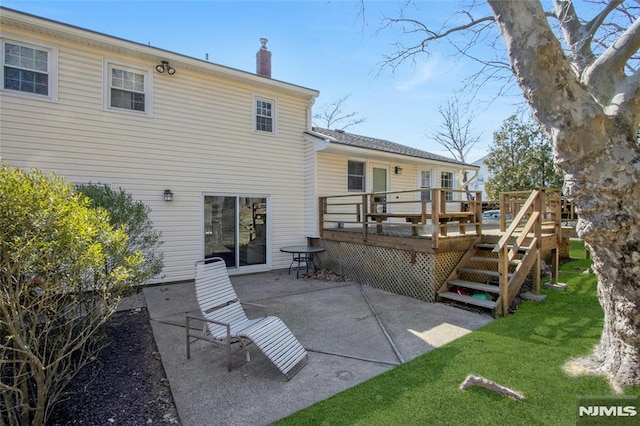 back of property featuring a deck, a yard, a patio area, and a chimney