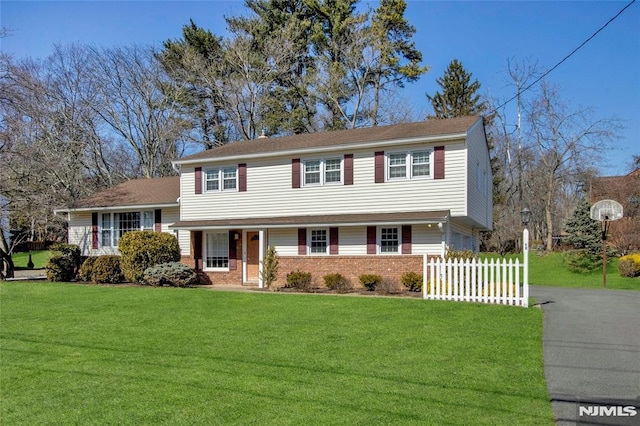 tri-level home featuring a front yard, fence, brick siding, and aphalt driveway