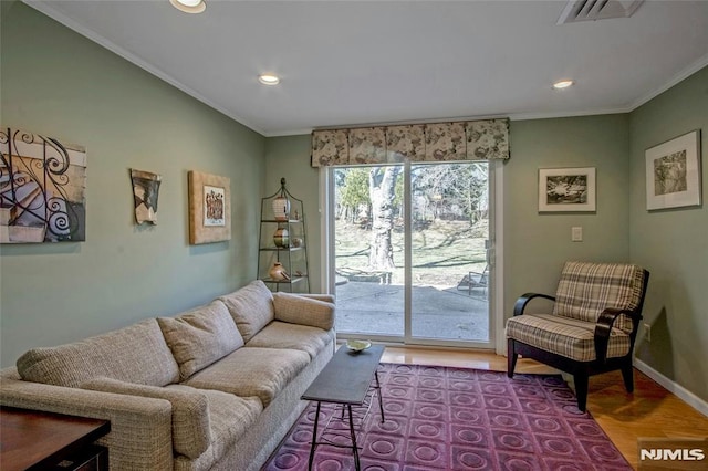 living room with visible vents, baseboards, ornamental molding, and light wood finished floors