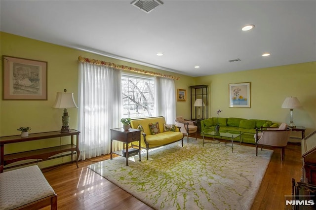 living area with visible vents, recessed lighting, and wood finished floors