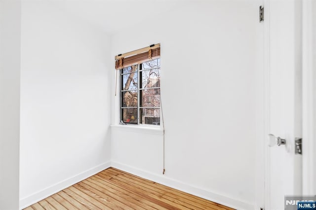 spare room featuring baseboards and light wood finished floors