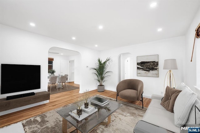 living room with recessed lighting, wood finished floors, arched walkways, and baseboards