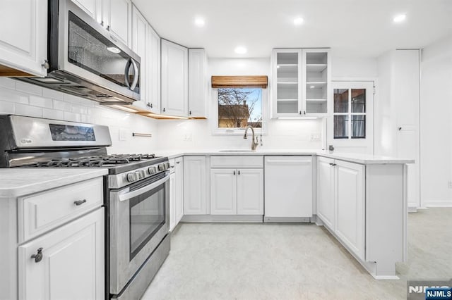 kitchen featuring decorative backsplash, white cabinetry, stainless steel appliances, and a sink