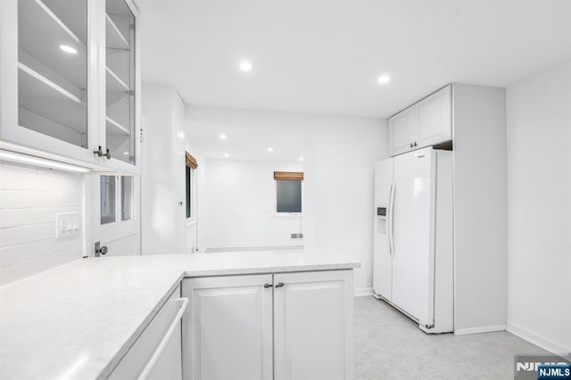 kitchen with white cabinetry, a peninsula, recessed lighting, and white fridge with ice dispenser