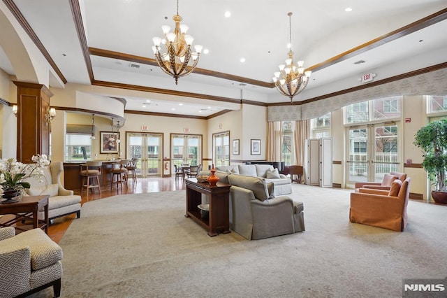 living area featuring a raised ceiling, plenty of natural light, french doors, and a chandelier