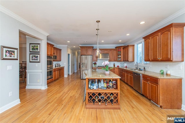 kitchen with brown cabinets, appliances with stainless steel finishes, light wood-style flooring, and a sink