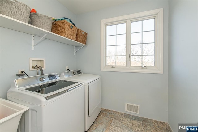 clothes washing area with laundry area, washing machine and dryer, visible vents, and a sink