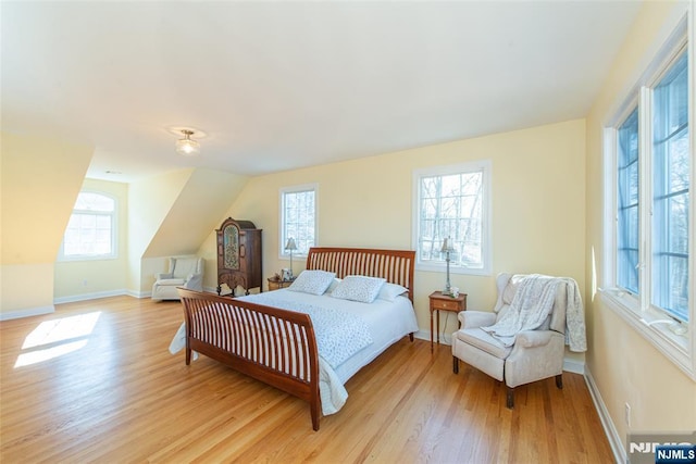 bedroom featuring vaulted ceiling, baseboards, and light wood finished floors