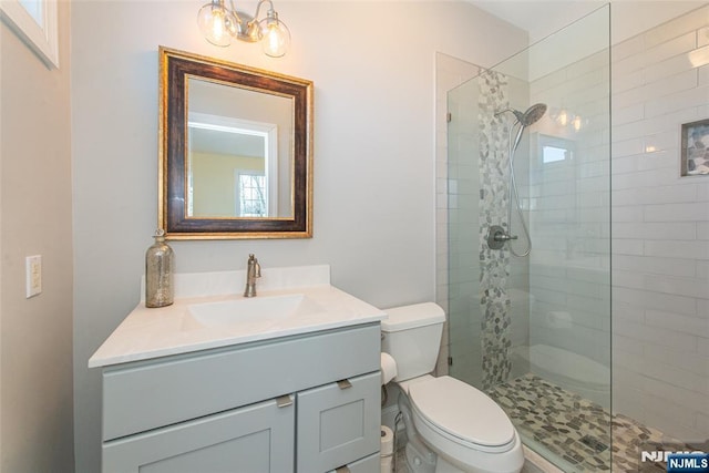 full bathroom with vanity, toilet, and tiled shower