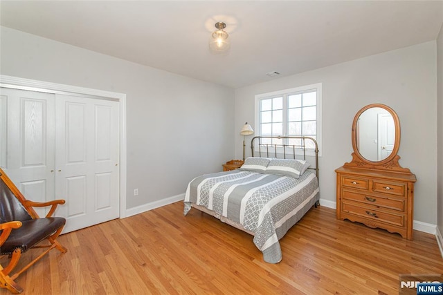 bedroom with light wood-type flooring, baseboards, a closet, and visible vents