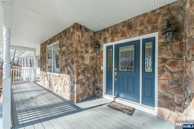 property entrance featuring a porch and stone siding