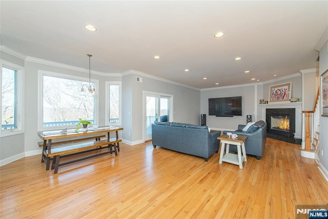 living area with baseboards, light wood-style flooring, a high end fireplace, and ornamental molding