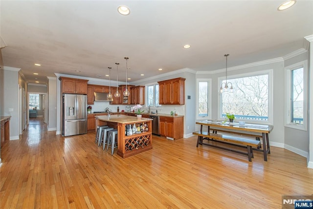 kitchen with brown cabinetry, light wood finished floors, decorative backsplash, under cabinet range hood, and appliances with stainless steel finishes