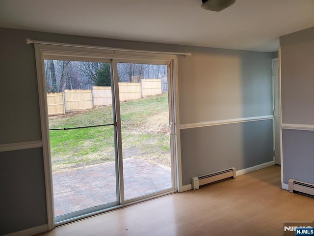 doorway to outside with wood finished floors, baseboards, and a baseboard radiator