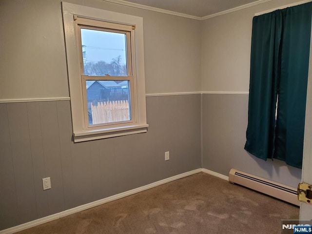 carpeted empty room with a wainscoted wall, crown molding, and a baseboard heating unit