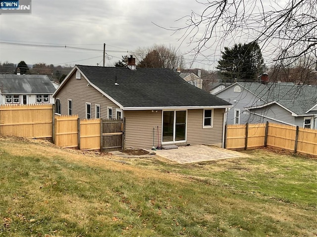 rear view of property featuring fence, roof with shingles, a chimney, a patio area, and a lawn