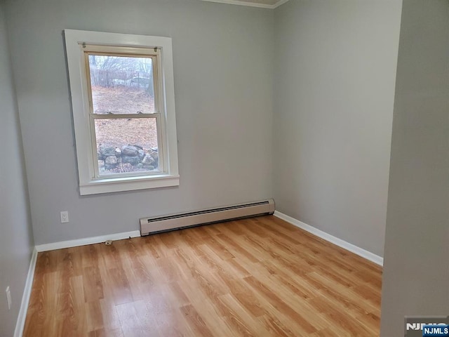 spare room with light wood finished floors, baseboards, and baseboard heating