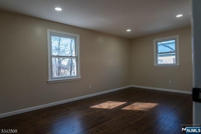 spare room featuring recessed lighting, baseboards, and dark wood-style floors