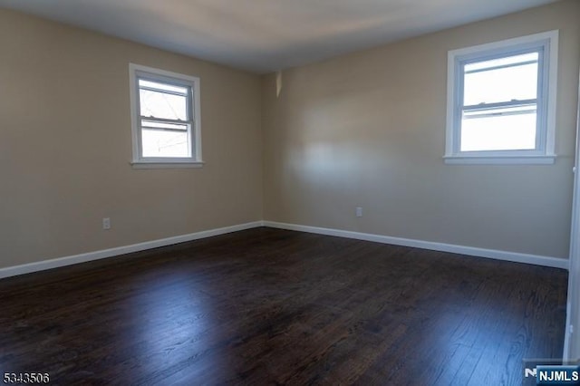 empty room with dark wood finished floors and baseboards