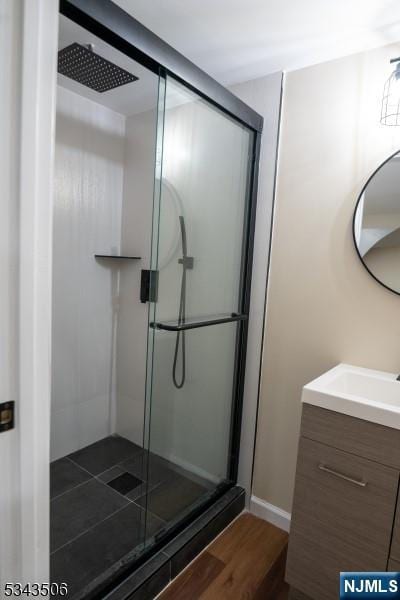 bathroom with vanity, wood finished floors, and a shower stall