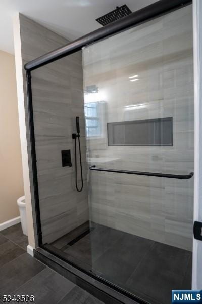 bathroom with tile patterned flooring, toilet, baseboards, and a stall shower