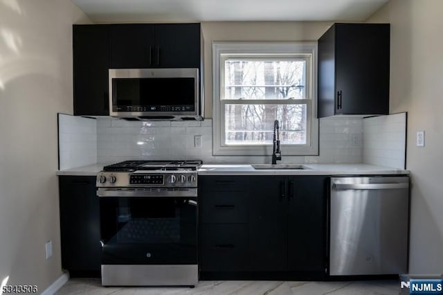 kitchen featuring a sink, appliances with stainless steel finishes, light countertops, and dark cabinets