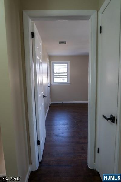 hallway with baseboards and dark wood-type flooring