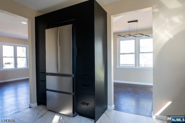 interior space with plenty of natural light, baseboards, dark cabinets, and freestanding refrigerator