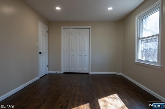 unfurnished bedroom with recessed lighting, baseboards, and dark wood-type flooring