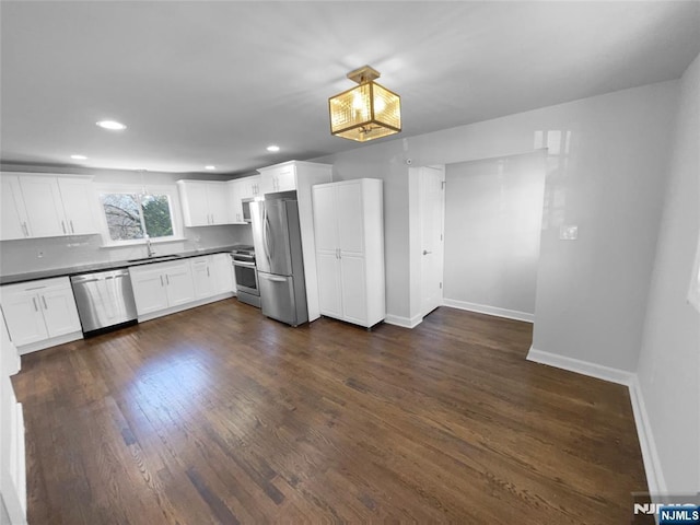 kitchen featuring dark countertops, dark wood-style floors, white cabinetry, appliances with stainless steel finishes, and baseboards